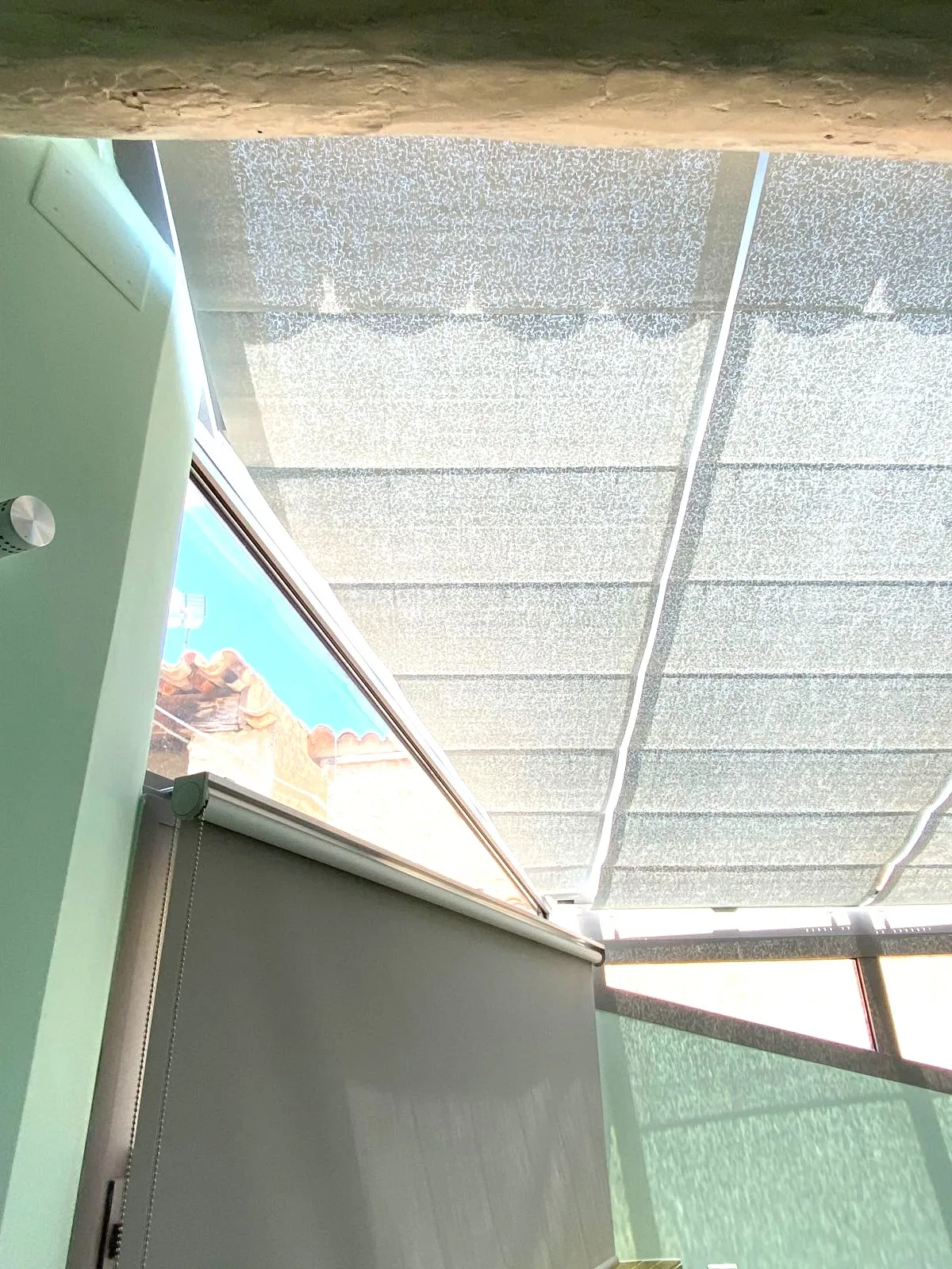Installation de stores solaires sur mesure dans une véranda à toiture vitrée