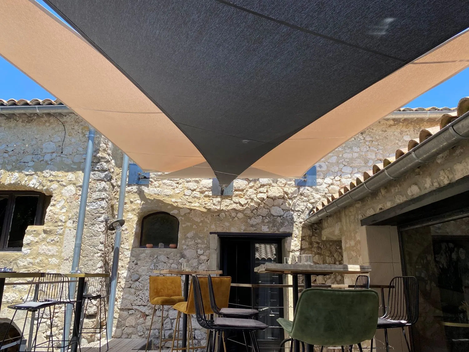 Double voile d'ombrage fixée dans un mur en pierre