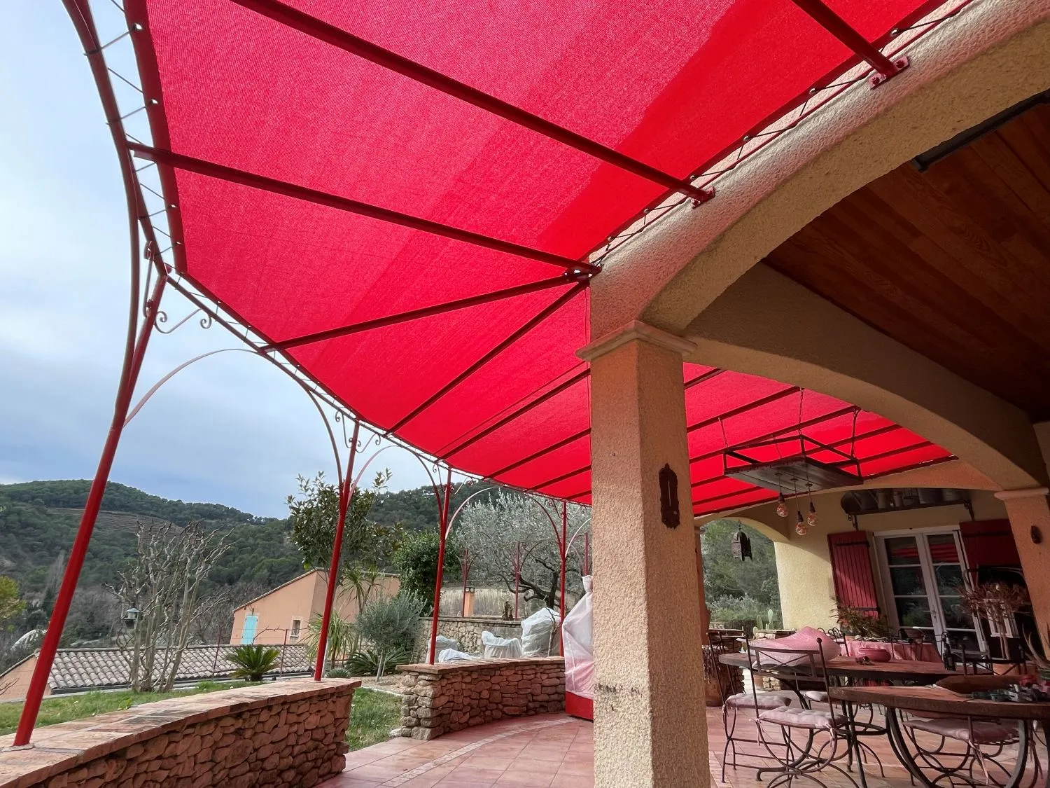 Toile tendue microperforée rouge sur pergola fer forgé à Nyons